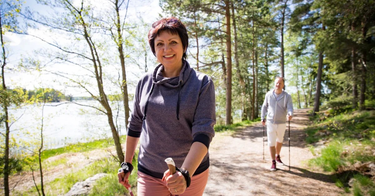 Dojrzała para uprawia nordic walking w słonecznym lesie